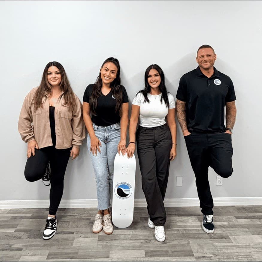 The Hillside Horizon family: four team members standing together, one holding a skateboard with the program logo