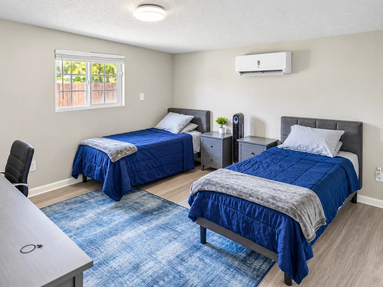 Richards bedroom with two twin beds in navy bedding, two nightstands, and a window to the backyard
