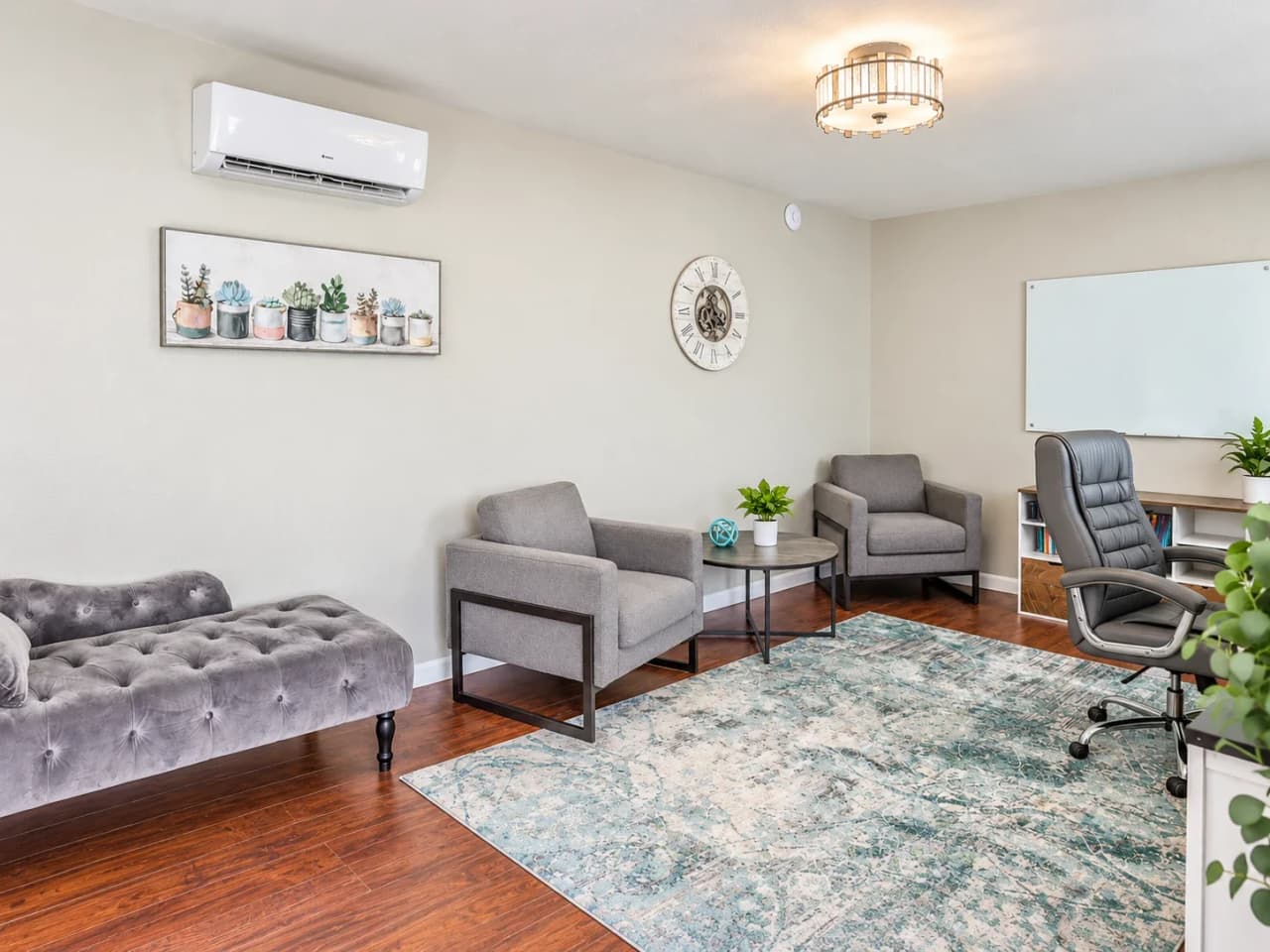Richards counseling room with a tufted chaise, two armchairs, a round coffee table, and a glass whiteboard