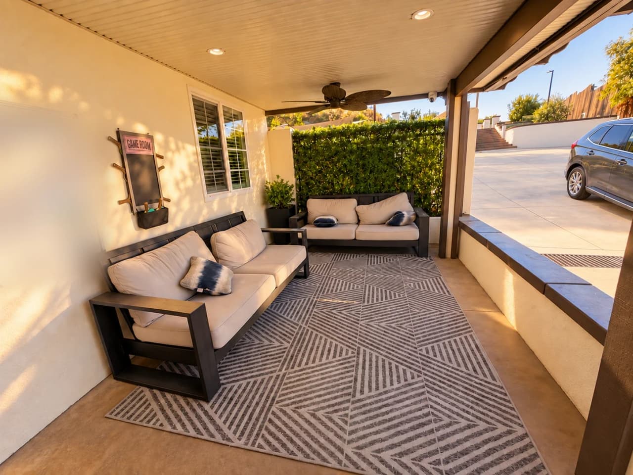 Richards covered patio lounge with two outdoor sofas, a patterned rug, and a game room board