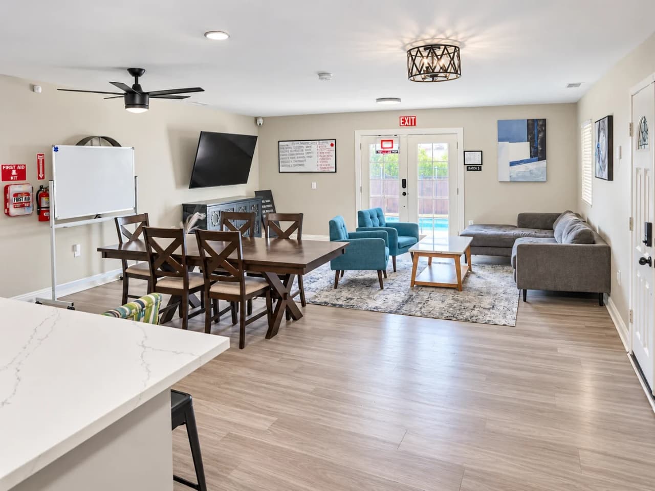 Richards great room with a dining table, a sectional sofa, teal armchairs, and French doors to the pool