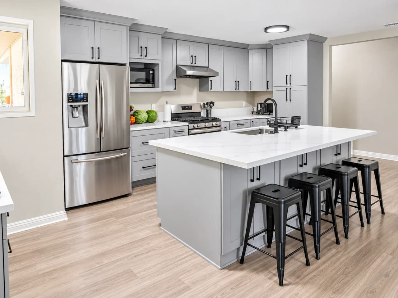 Richards white kitchen with a quartz island, black bar stools, and stainless appliances