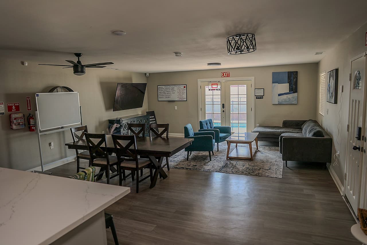Richards common room with a dining table, sofa, and doors to the pool