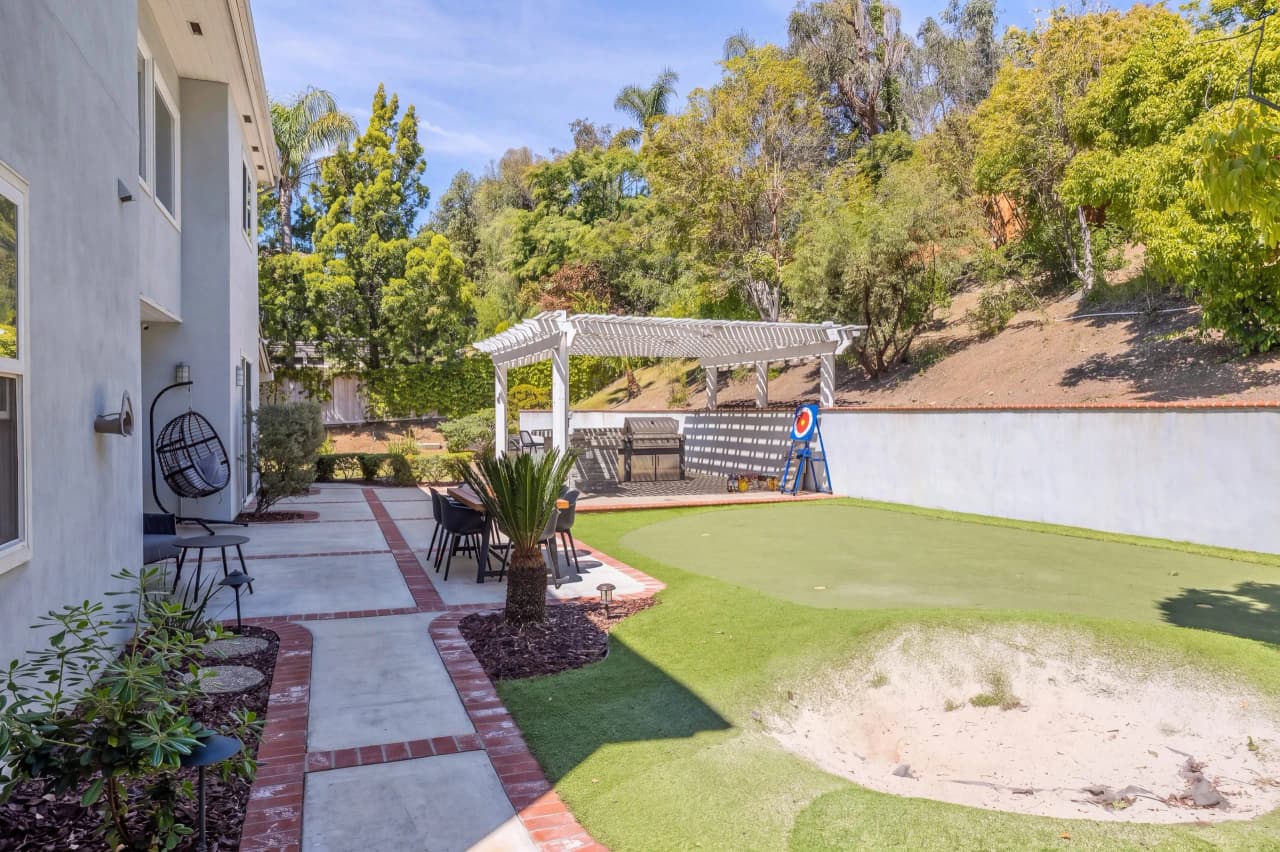 Ridgeview backyard with a putting green and a white pergola