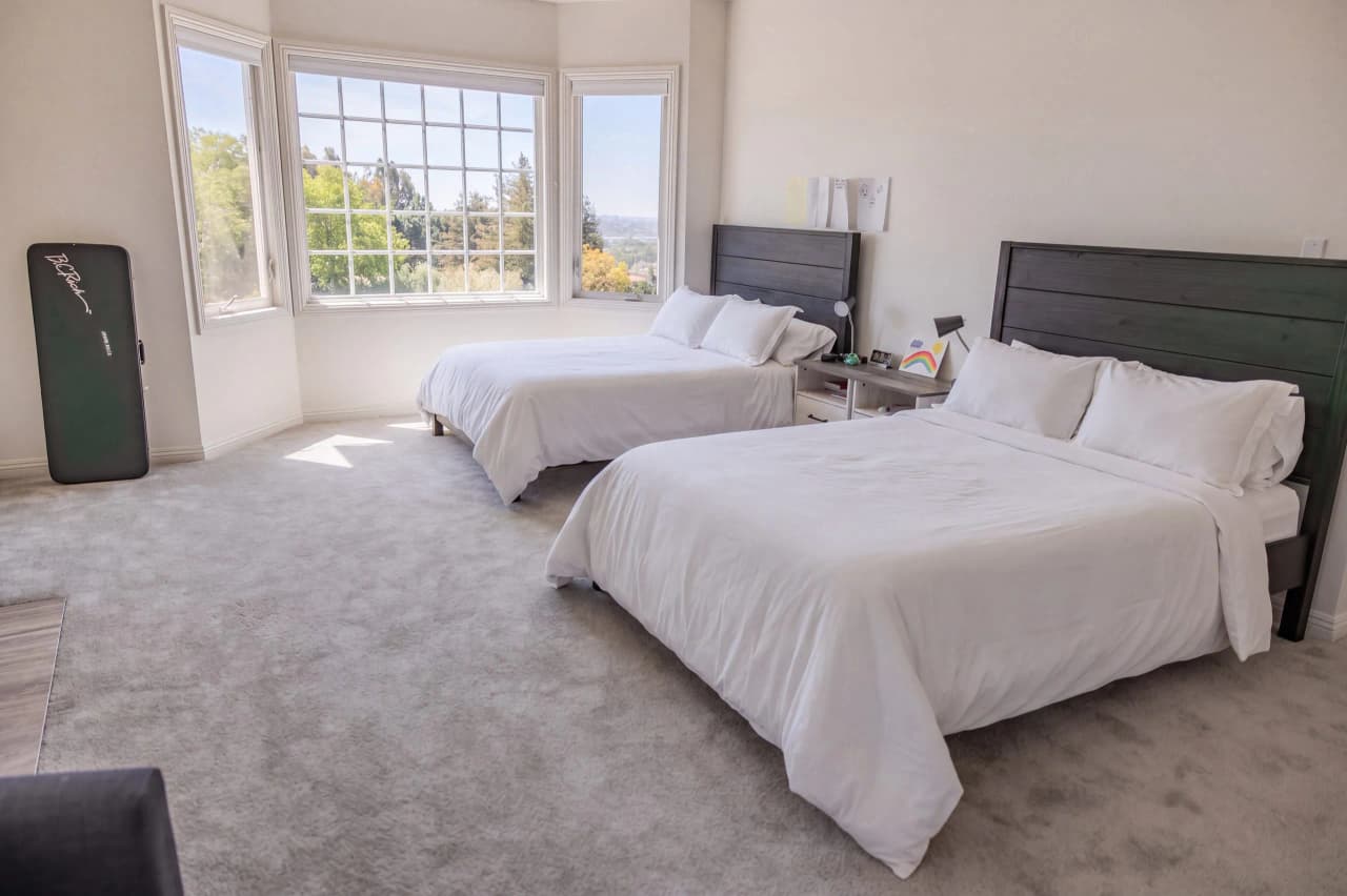 Ridgeview bedroom with two beds in white bedding beside a bay window