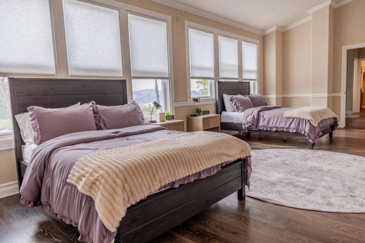 Shasta bedroom with two beds in lavender bedding and large windows