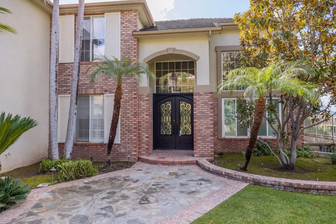 Shasta house front walk with brick columns, iron double doors, and palm trees