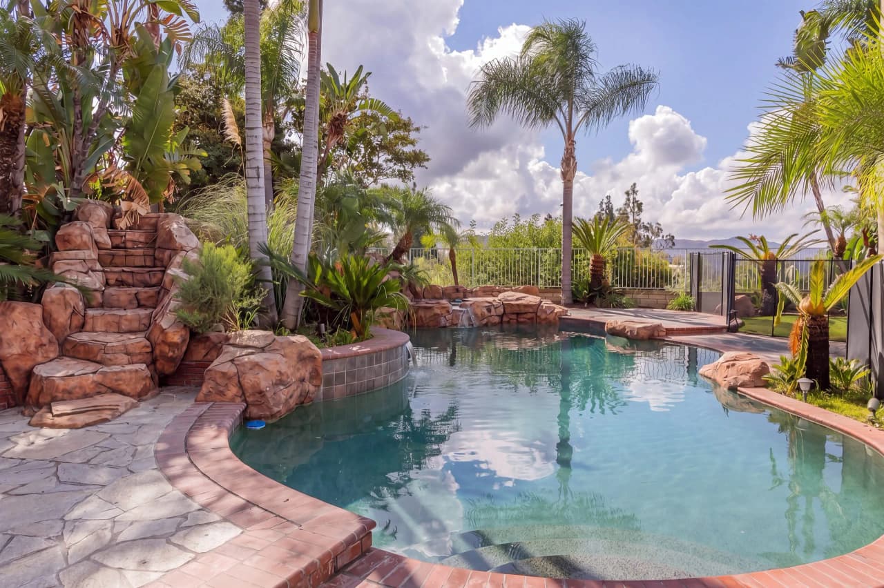 Shasta backyard pool with a rock waterfall and palm trees