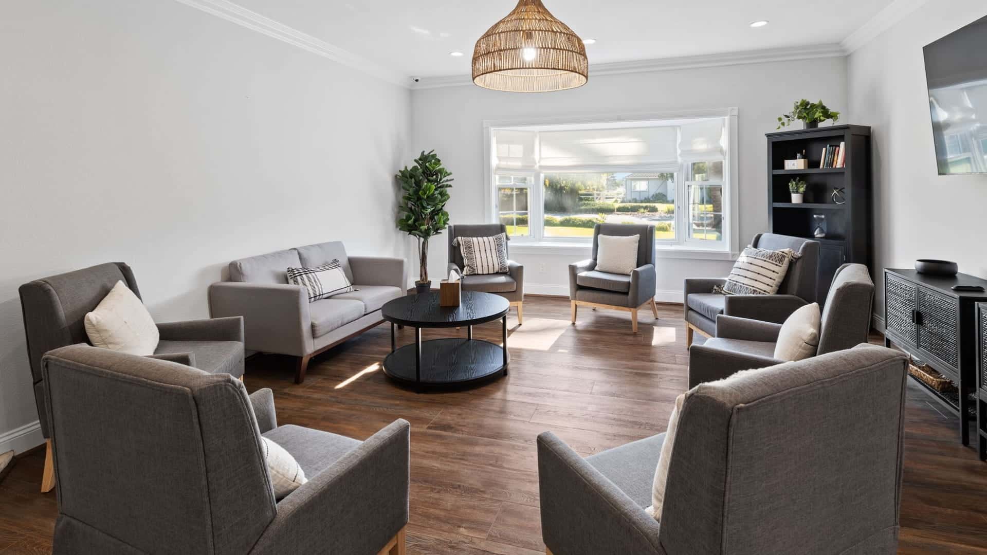 Comfortable group therapy room with circle seating, sofa, natural light, and calming decor in a mental health facility.